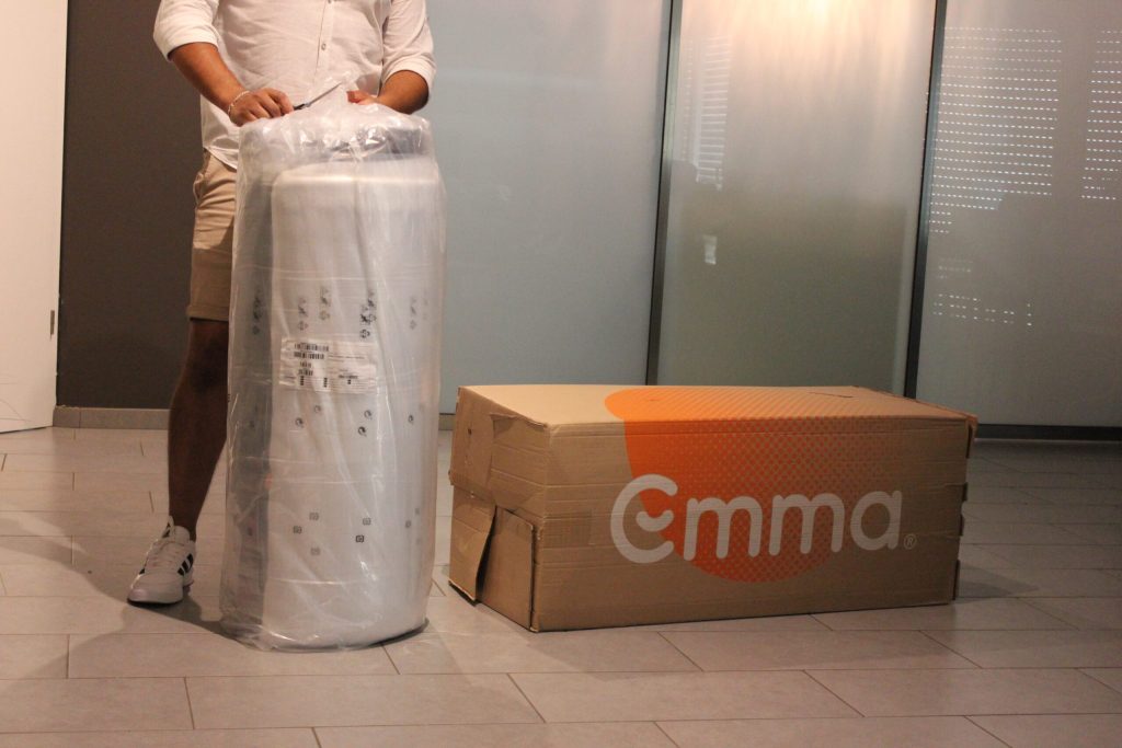 Unboxing der Emma Original Matratze: gerollte Matratze neben dem Emma Karton