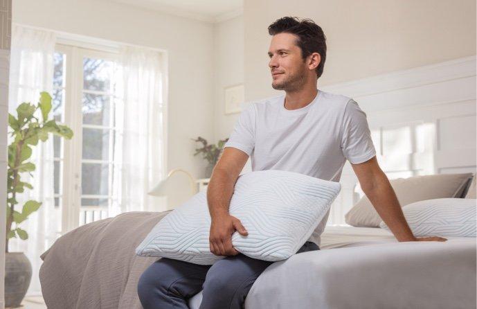 TEMPUR Comfort SmartCool Schlafkissen wird auf einem Bett im Schlafzimmer gehalten