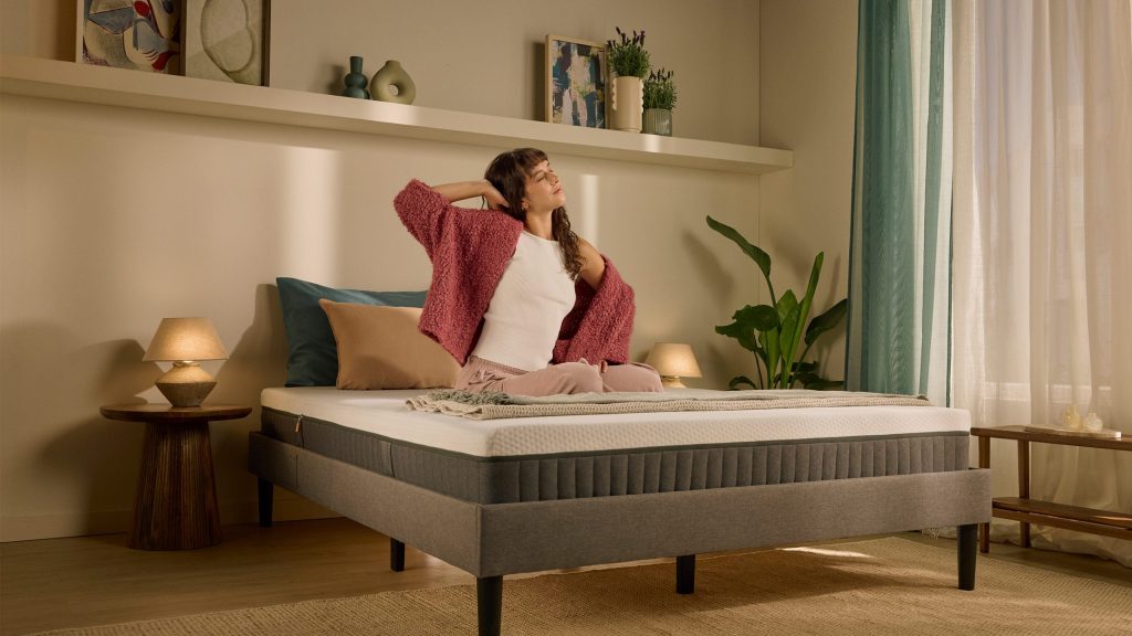 Frau sitzt auf der Emma Original Lite Matratze im Schlafzimmer