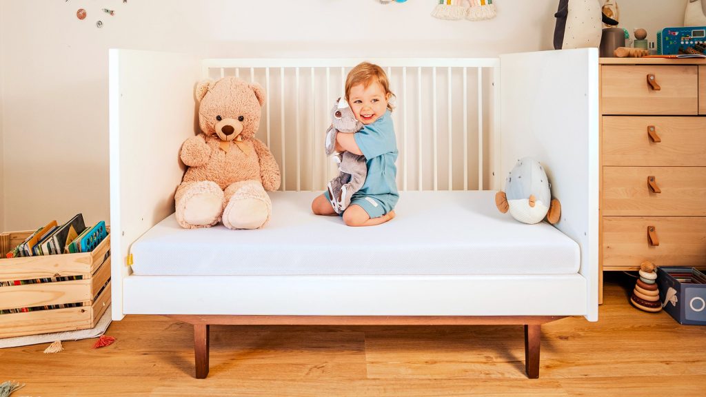 Emma Kindermatratze – Kleinkind sitzt auf der Matratze im Kinderbett