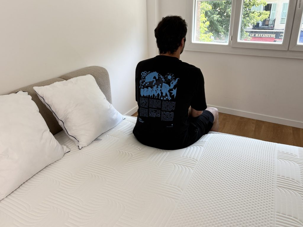 Tester sitzt auf dem Bett, dahinter zwei Emma Original Comfort Kissen