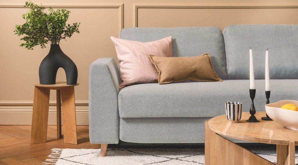 Bruno Ecksofa in Hellgrau mit Kissen und Beistelltisch im Wohnraum