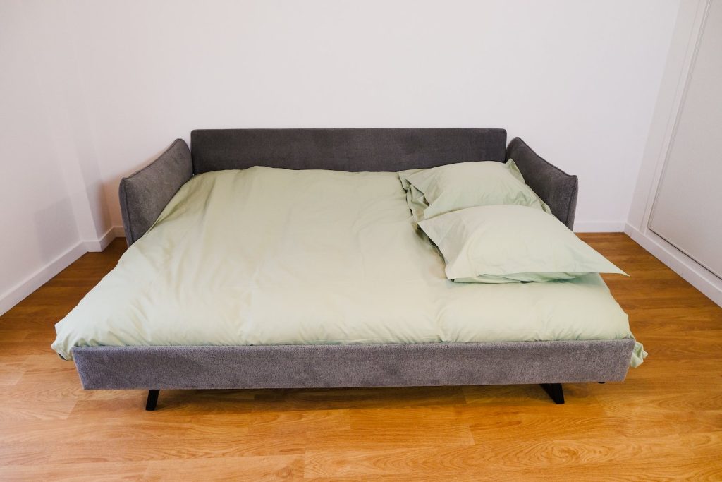 Ausgeklapptes Emma Original Schlafsofa mit grüner Bettwäsche und Kopfkissen