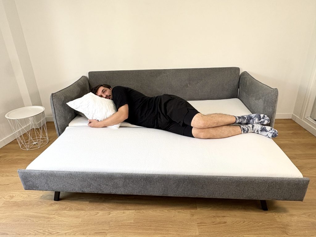 Tester liegt in Seitenlage auf dem ausgeklappten Emma Original Schlafsofa