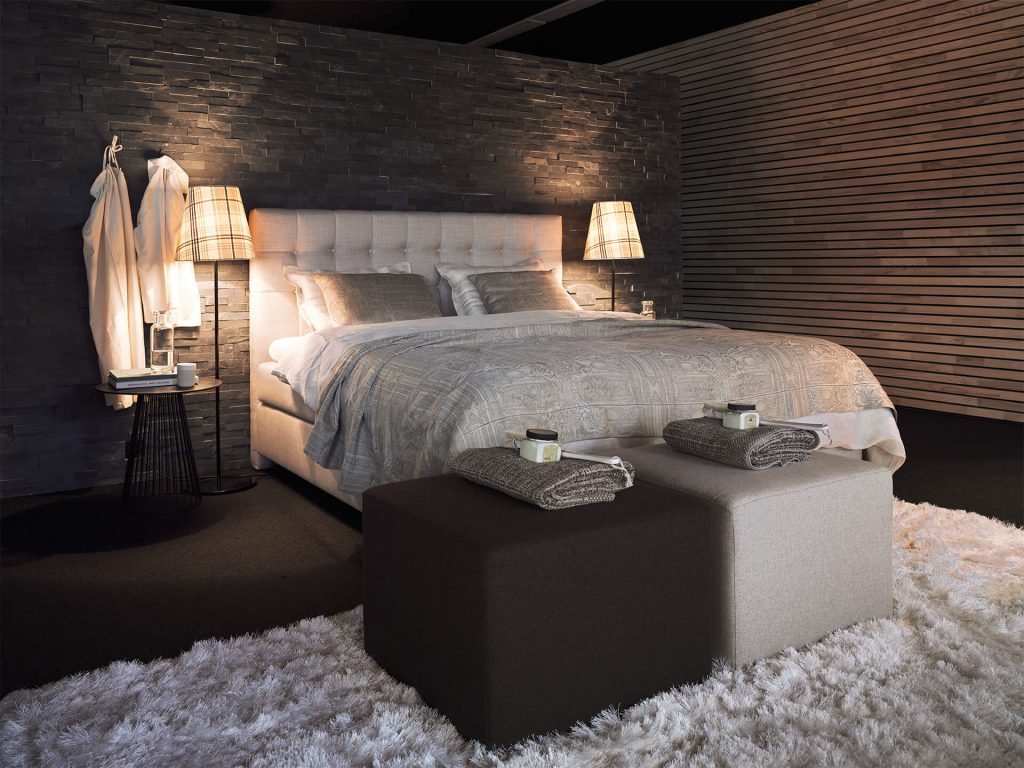 Joka Boxspringbett Noblesse in Creme vor dunkler Steinwand
