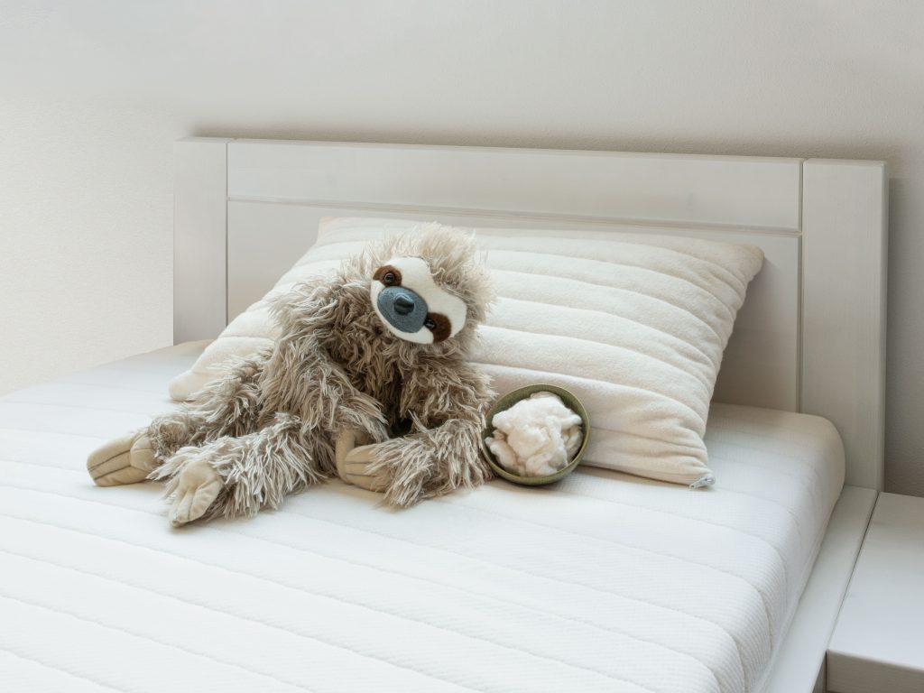 allnatura Kinderkopfkissen Cotona-Medicott auf einem Kinderbett mit Kuscheltier