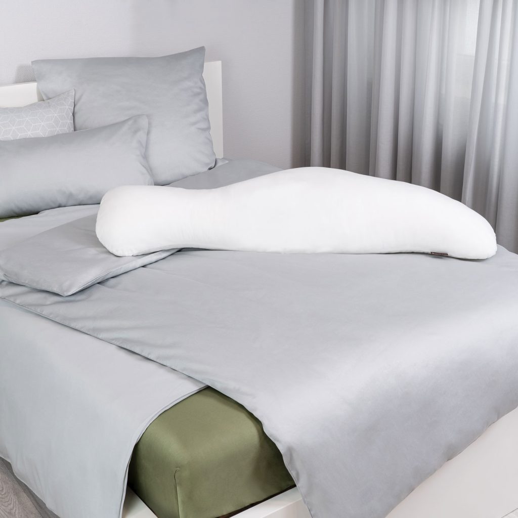 Centa-Star Hippo Seitenschläferkissen auf einem Bett mit grauer Bettwäsche