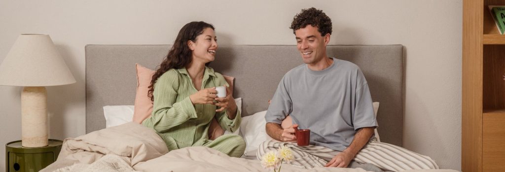 Paar frühstückt im Bett mit Bruno Bettwäsche in Beige