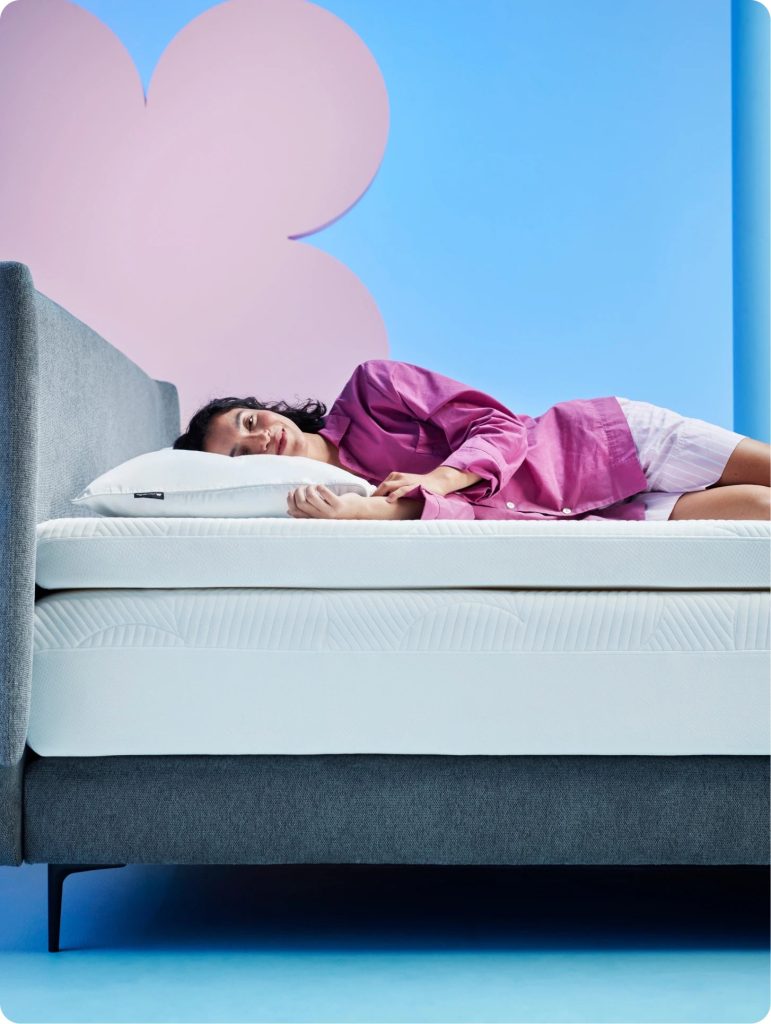 Frau schläft auf dem Cloudpillo Plus Topper auf einem Polsterbett