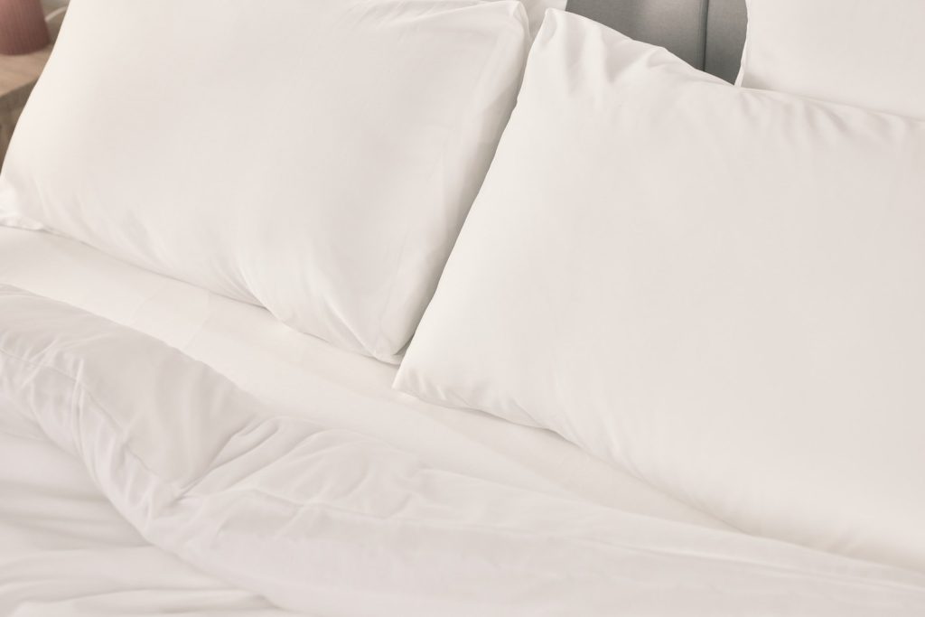 Emma Satin-Kissenbezüge in Weiß auf dem Bett