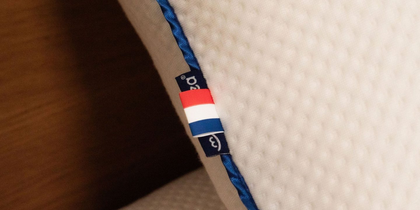 Kissenkante mit blauer Paspel und eingenähtem Etikett in Nahaufnahme