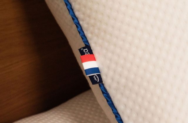 Kissenkante mit blauer Paspel und eingenähtem Etikett in Nahaufnahme