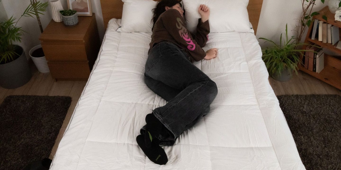 Person schläft in Seitenlage auf einem Bett, von oben fotografiert