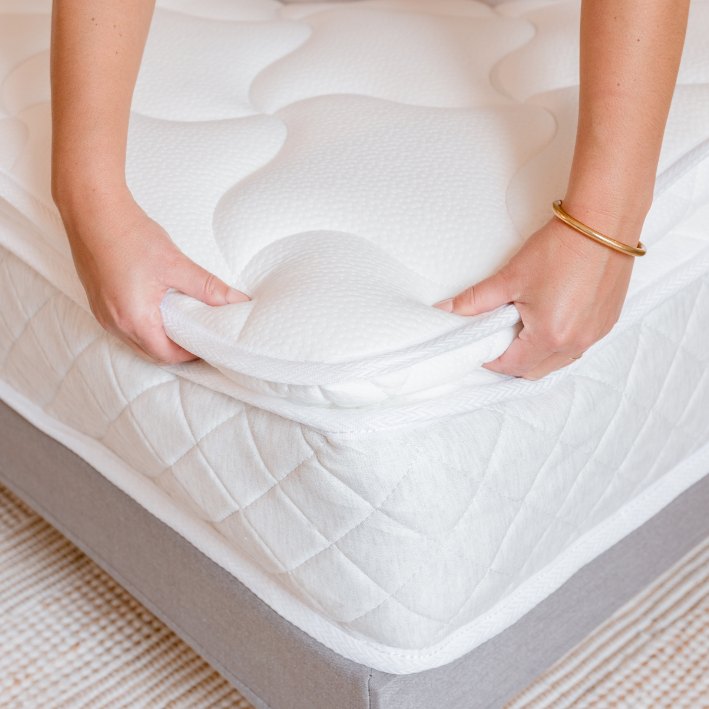 Slome Matratze H3 Wellness Supreme – Hände heben die Kante der Komfortauflage an